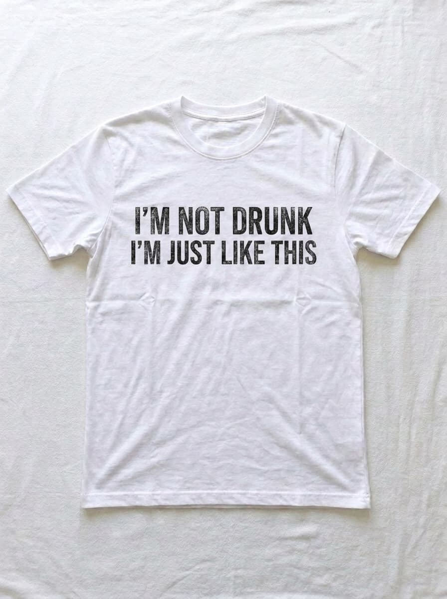 Back of a white t-shirt printed in distressed black type with I'M NOT DRUNK I'M JUST LIKE THIS.