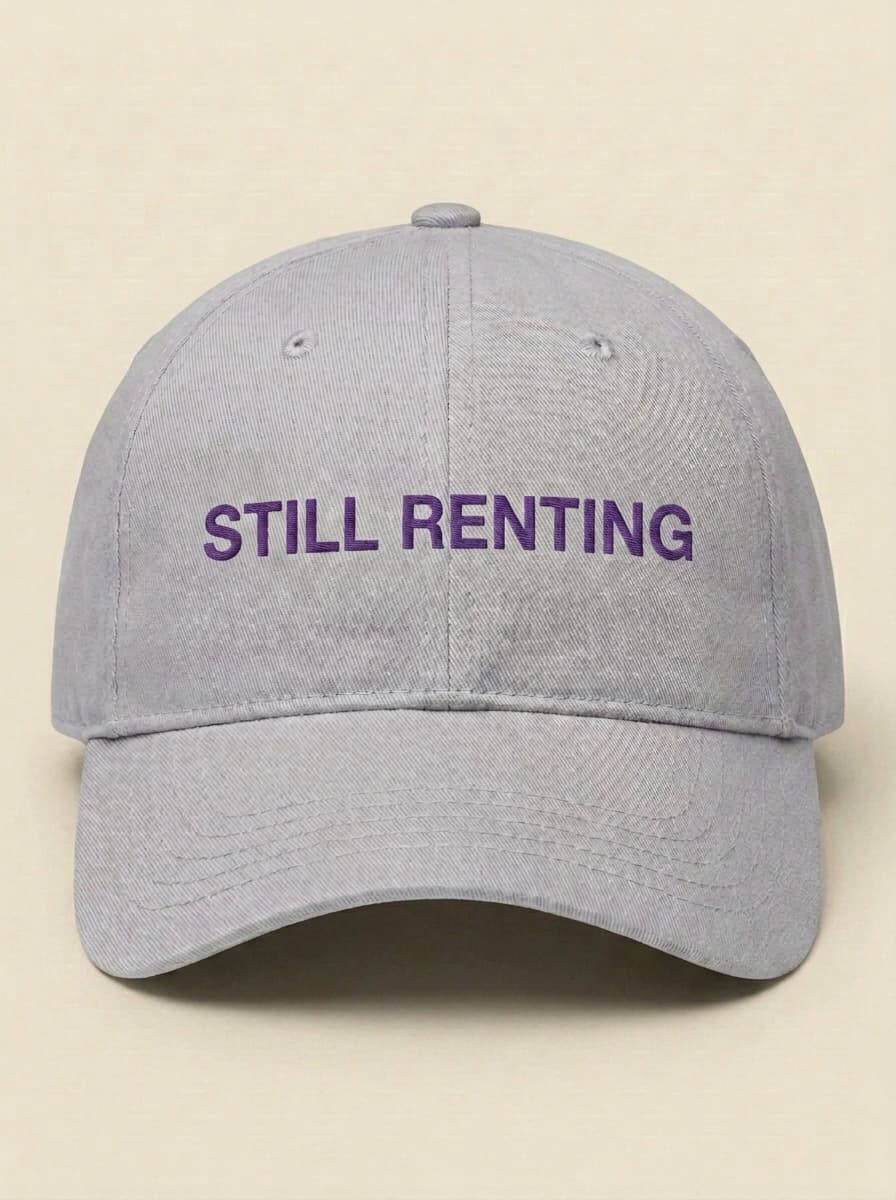 Light grey dad hat embroidered in purple with STILL RENTING.