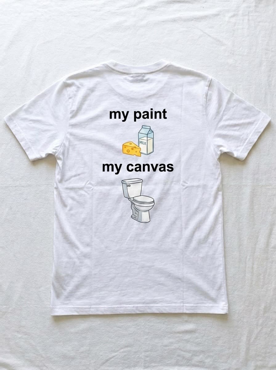 Back of a white t-shirt printed with the words my paint above a carton of milk and a wedge of cheese, and the words my canvas above a toilet.